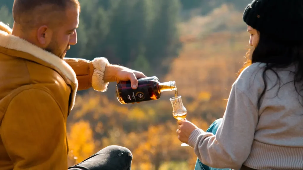 Sipanje rakije u čašu u jesenjem ambijentu na Goliji